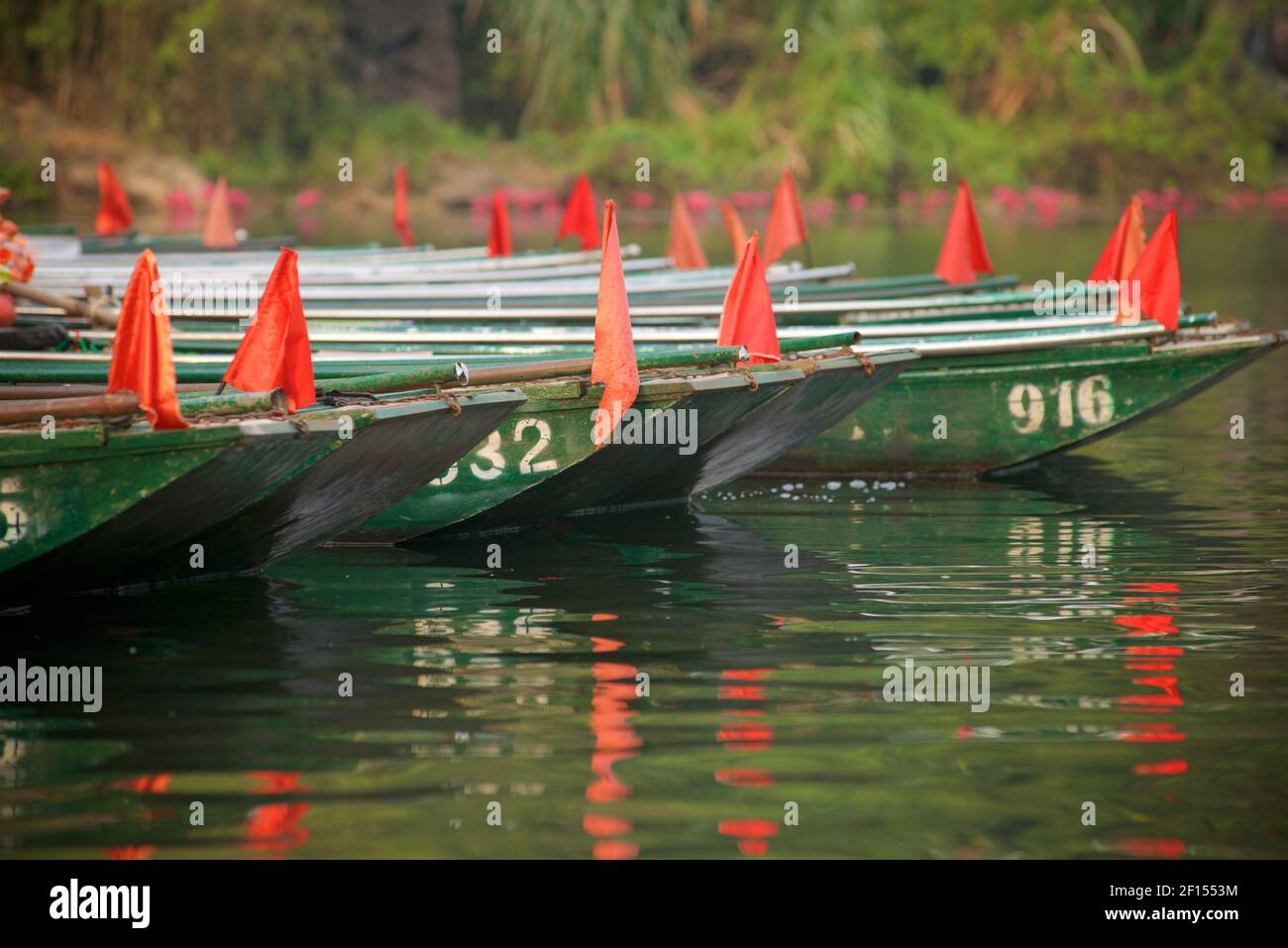 Boote Reihen sich auf dem Flussufer, bereit für touristische Ausflüge rund um die Trang an Scenic Landscape Complex, Ninh Binh, Vietnam Stockfoto