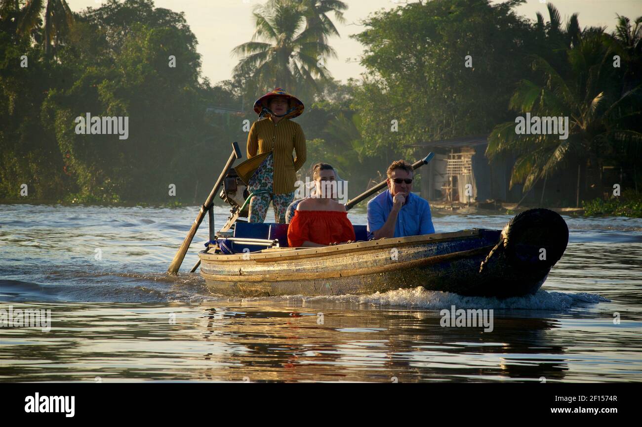Ein westliches Paar, das auf einem hölzernen Kanu zwischen dem frühmorgendlichen schwimmenden Markt in Phong Điền, zu dem von Cai Rang fährt. Mekong Delta, Vietnam Stockfoto