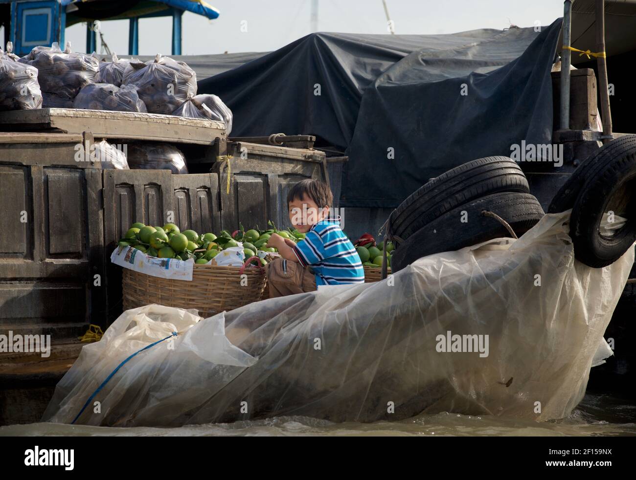 Vietnamesischer Junge auf einem Flussboot, Handel mit Pomelo Obst auf Cai Rang schwimmenden Markt, Mekong Delta, Vietnam Stockfoto