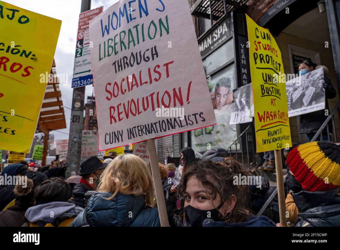 Ein Protestant hält während der Demonstration Plakate mit der Aufschrift, dass Frauen durch sozialistische Revolution befreit werden.die Liox Cleaners-Kette steht nach dem angeblichen "Gewerkschaftsbruch" vor einer Menge Opposition. Laut der verteilten Literatur, "am 19. Februar, die Liox-Wäscherei-Kette entlassen die eingewanderten Arbeiterinnen der Wash Supply Waschsalon. Die Eigentümer haben die Upper West Side geschlossen und die Maschinen weggenommen." Die Arbeiter versuchten angeblich, eine Gewerkschaft zu organisieren, und behaupten, dass dies der Antrieb für ihre Kündigung sei. Stockfoto