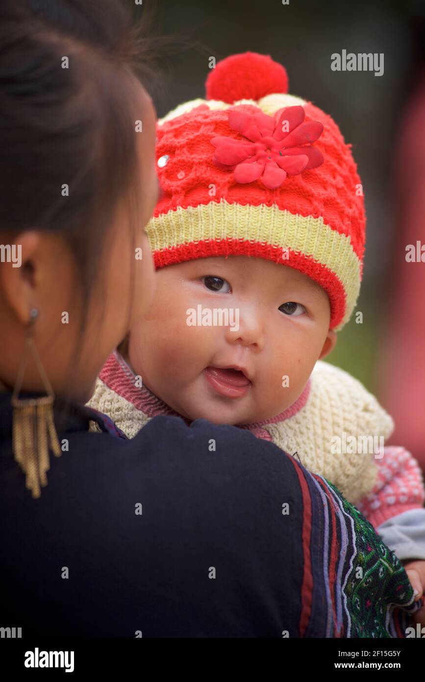 Vietnamesische Frau, die ein kleines Kind trägt, Sapa, Provinz Lao Cai, Nordvietnam. Hmong Hilltribe. Stockfoto