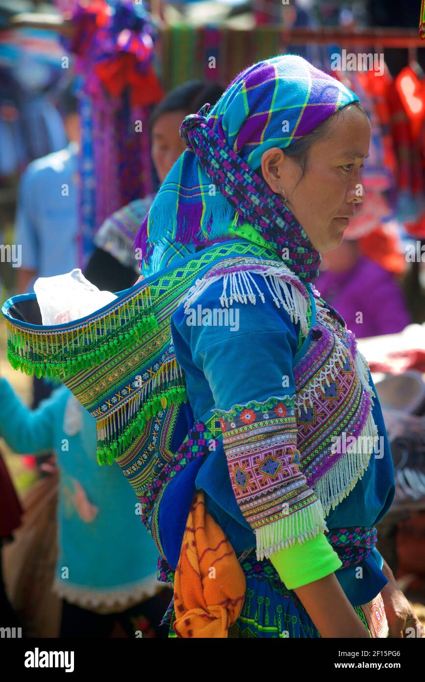 Blume Hmong Frau mit Baby auf dem Rücken auf dem Markt in Can CAU, Lao Cai Provinz. nordvietnam. Tribal-Kleidung Stockfoto