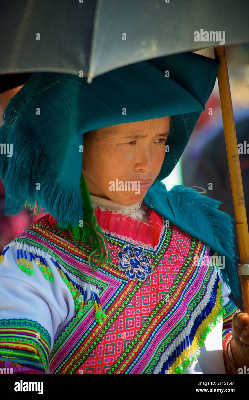 Blume Hmong Frau in indigenen Kostüm mit Sonnenschirm auf Can CAU Markt, Lao Cai Provinz, Vietnam. Stockfoto