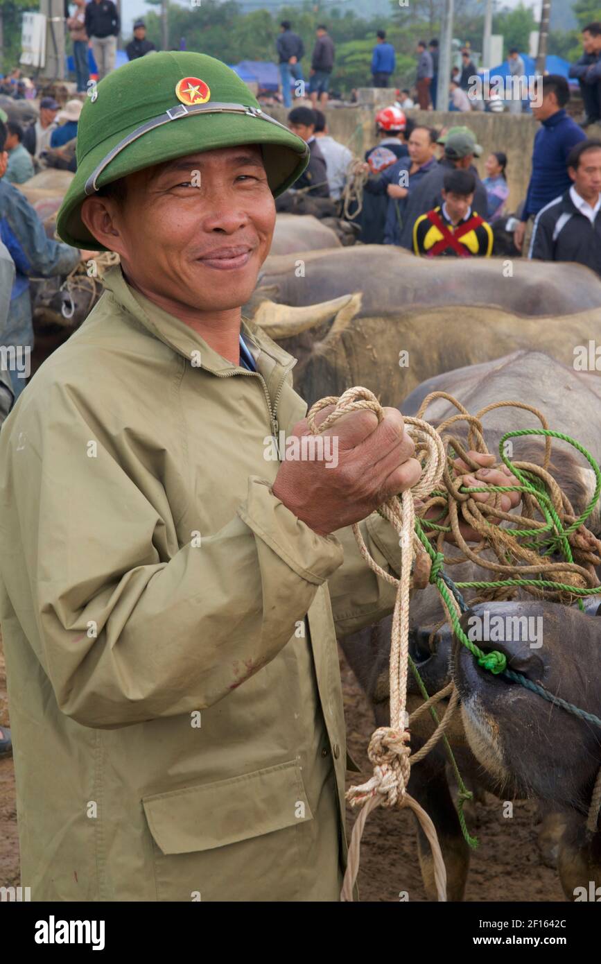 Viehmarkt. Lächelnder vietnamesischer Mann in markanter Armee, der Wasserbüffel auf dem Bac Ha Markt in der Provinz Lao Cai im Nordosten Vietnams verkauft Stockfoto