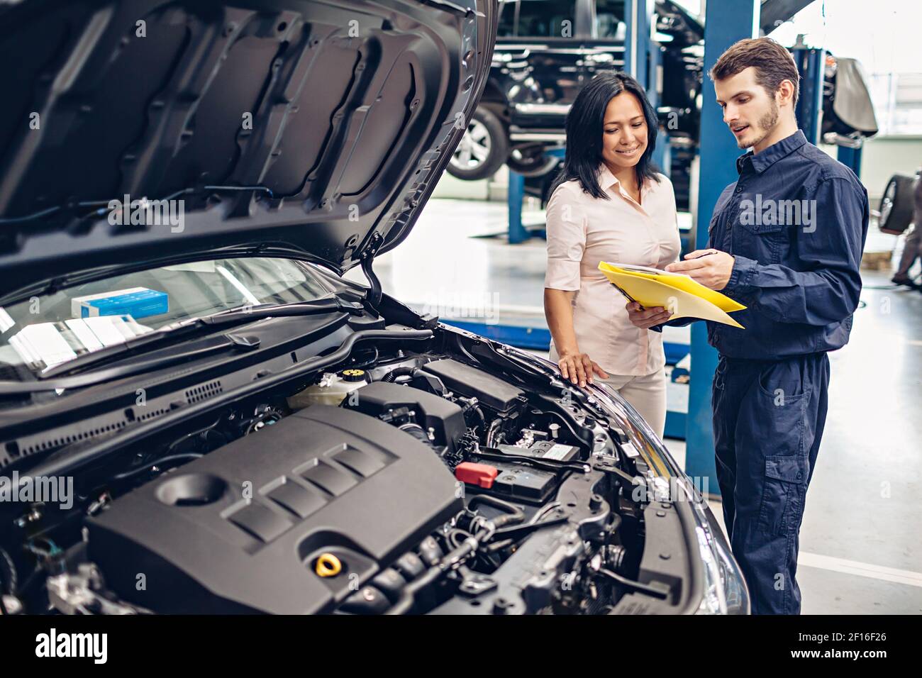 Car Service Center Szene. Der Mechaniker kommuniziert mit dem Kunden Stockfoto