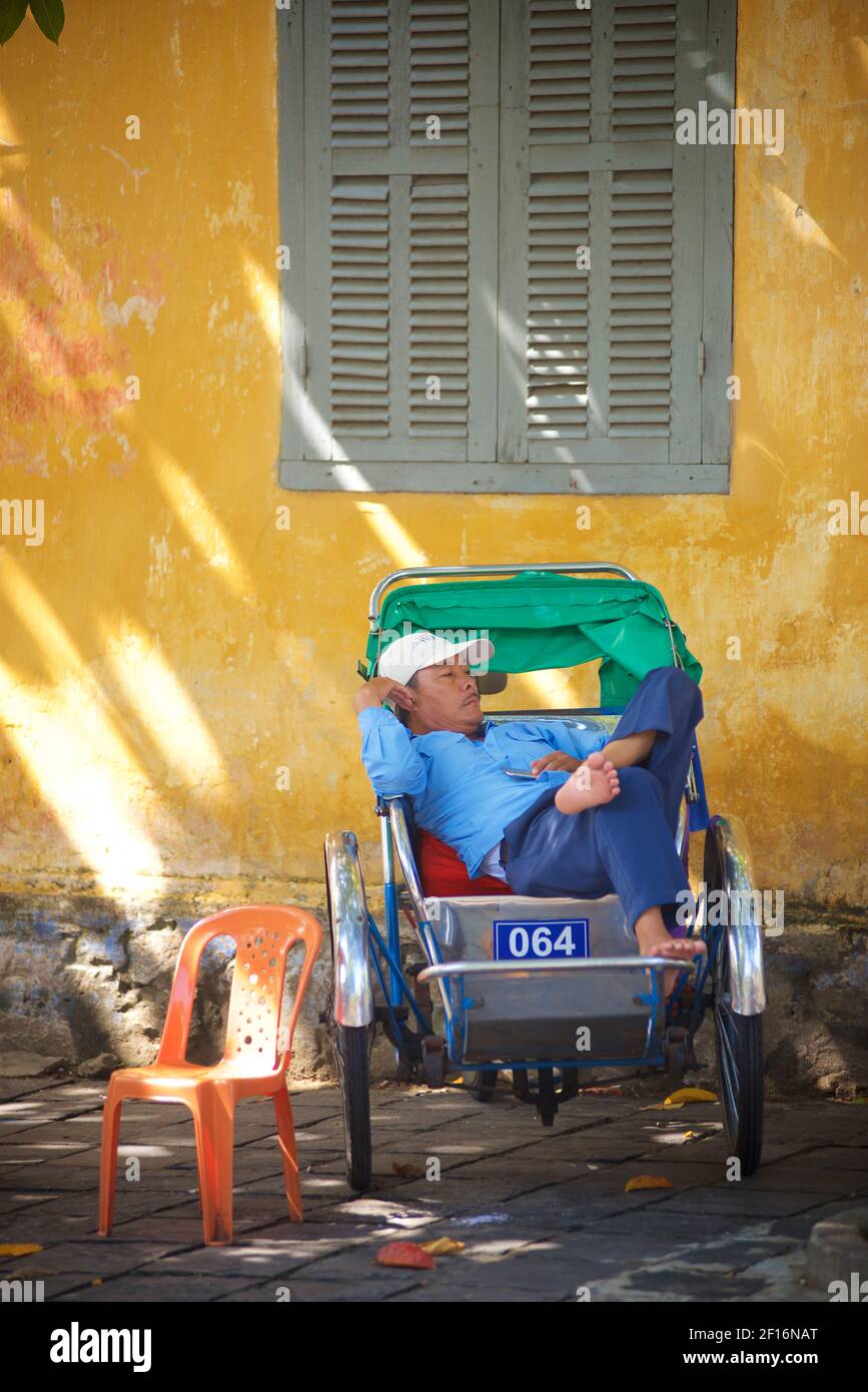Vietnamesischer Rikscha-Fahrer, der in seiner Rikscha ruht. Hoi An, Vietnam Stockfoto