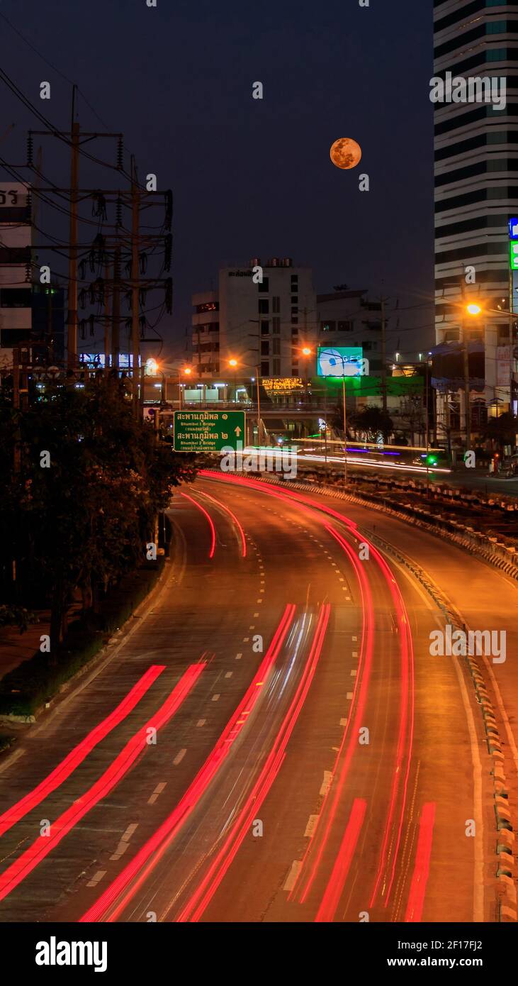 Vollmond über der Straße mit roten Rücklichtswegen Stockfoto