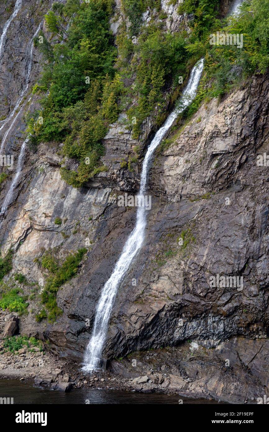 Schlanker Wasserfall mit Felsen und Bäumen Stockfoto