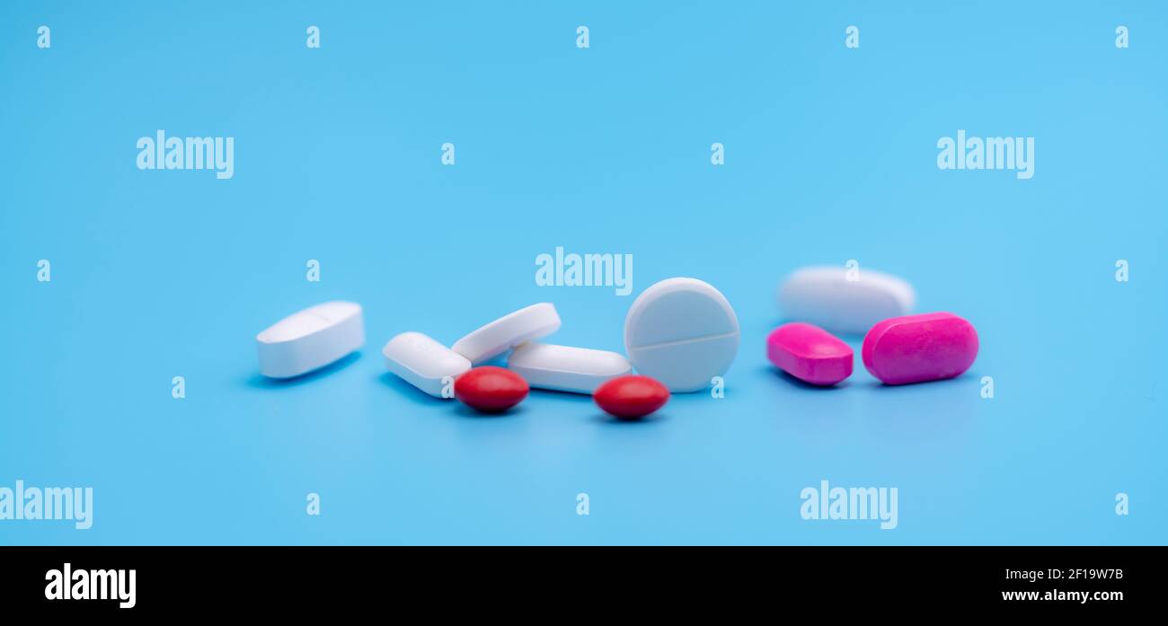 Apothekenbanner. Weiße und rosa Tabletten Pillen auf blauem Hintergrund. Runde und ovale Tabletten. Schmerzmittel. Acetaminophen und Ibuprofen Tabletten. Stockfoto