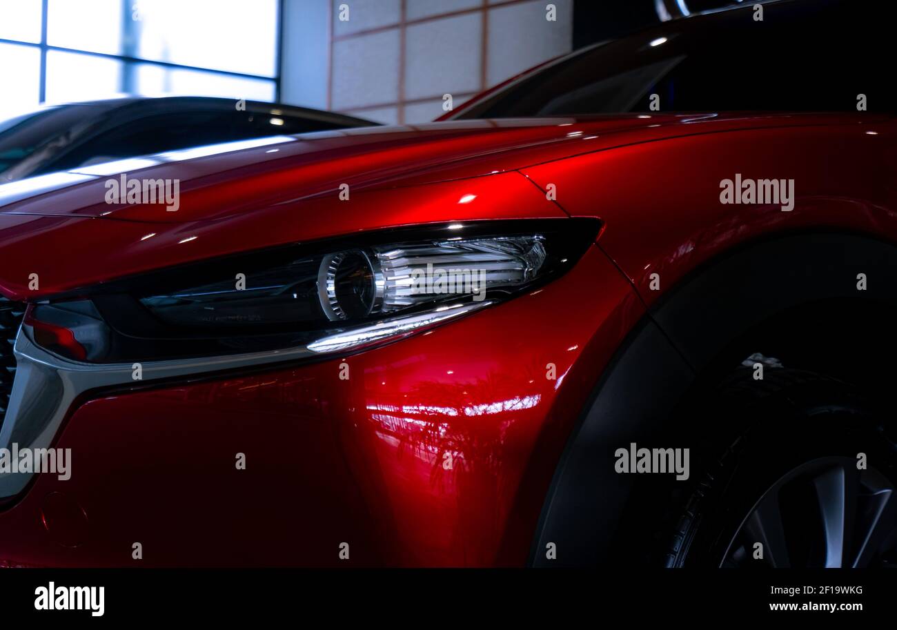 Nahaufnahme Scheinwerfer von glänzend roten Luxus-SUV-Auto im Showroom. Elegantes Elektroauto mit Sportdesign. Auto im Ausstellungsraum geparkt. Autohaus. Elektrische Ve Stockfoto Nahaufnahme Scheinwerfer von glänzend roten Luxus-SUV-Auto im Showroom. Elegantes Elektroauto mit Sportdesign. Auto im Ausstellungsraum geparkt. Autohaus. Elektrische Ve Stockfoto