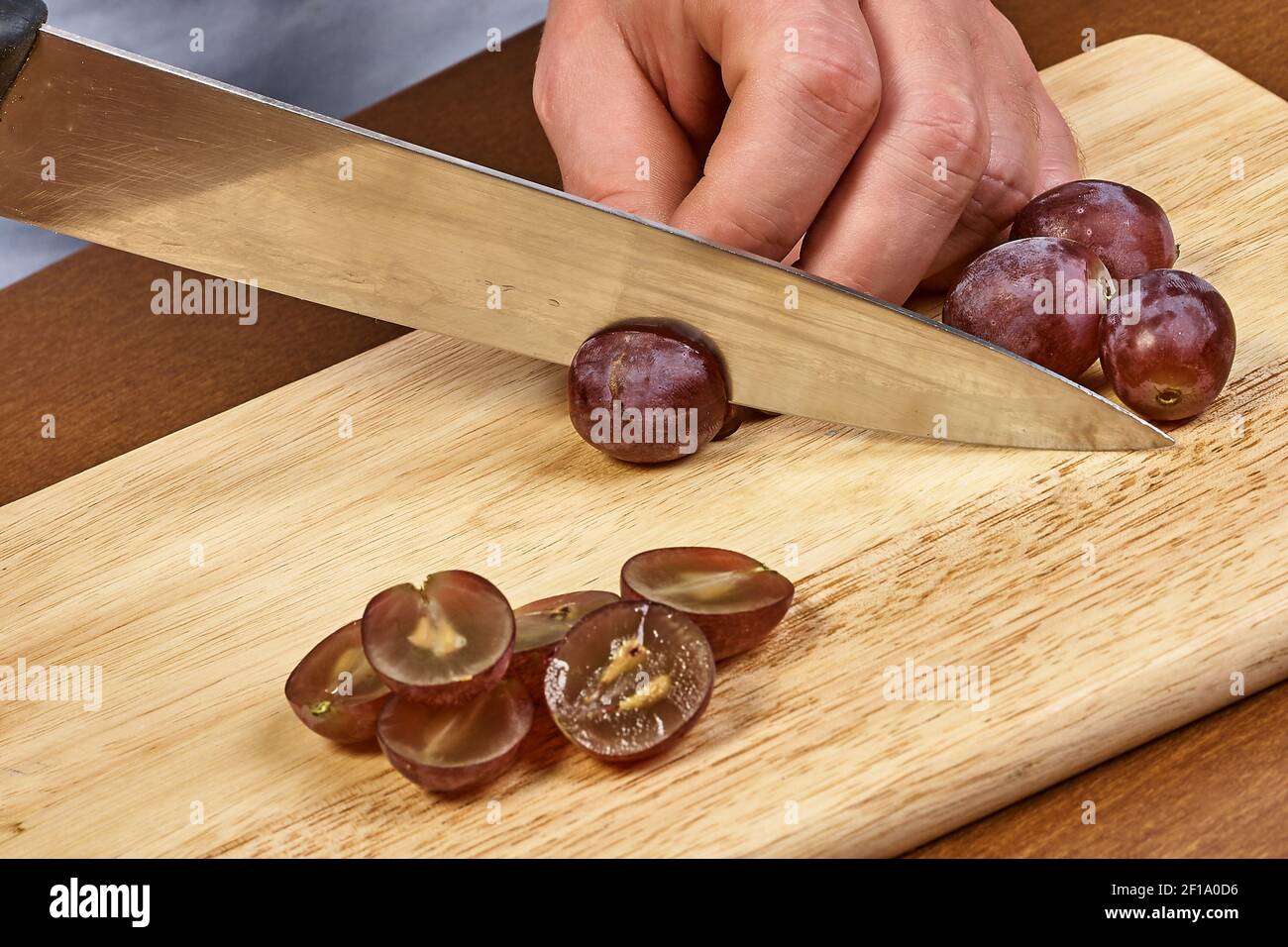 Koch Schnitt Trauben auf einem Schneidebrett Hand des Küchenchefs Close-Up Stockfoto