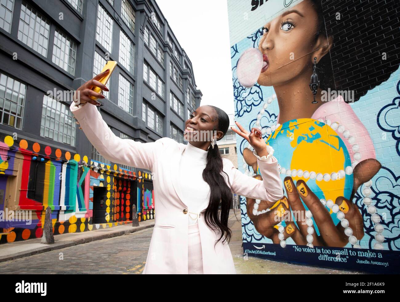 REDAKTIONELLE VERWENDUNG NUR Jonelle Awomoyi mit einem Wandbild von sich  selbst von der Künstlerin Rosie Woods gemalt, die im Rahmen der  #TheArtOfMobruderschaft Serie von Amazon Handmade Marking motherÕs Day  geschaffen wurde, um