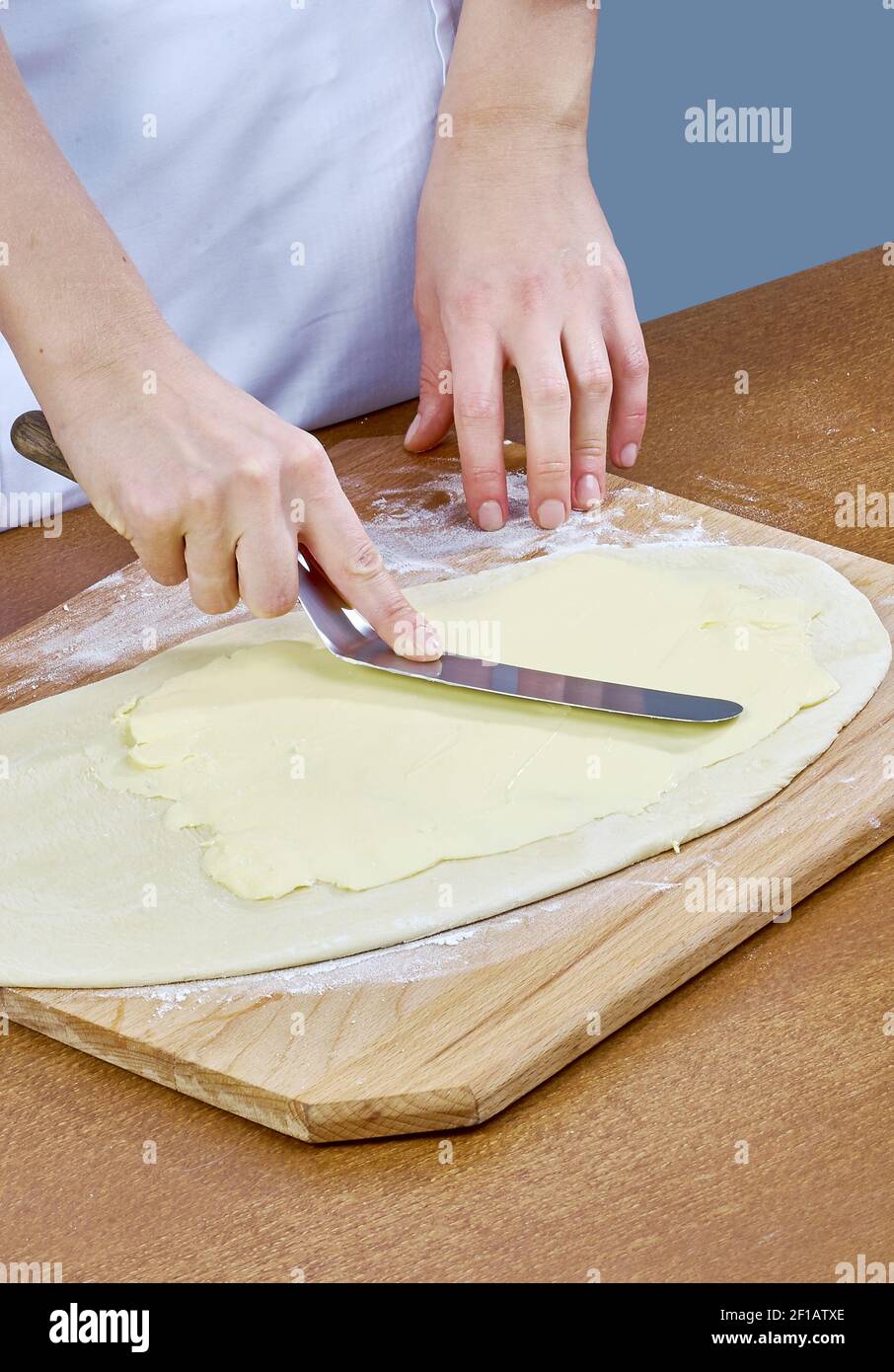 Der Koch schmiert Butter auf den Teig für die Zubereitung Backen Kochen Stockfoto