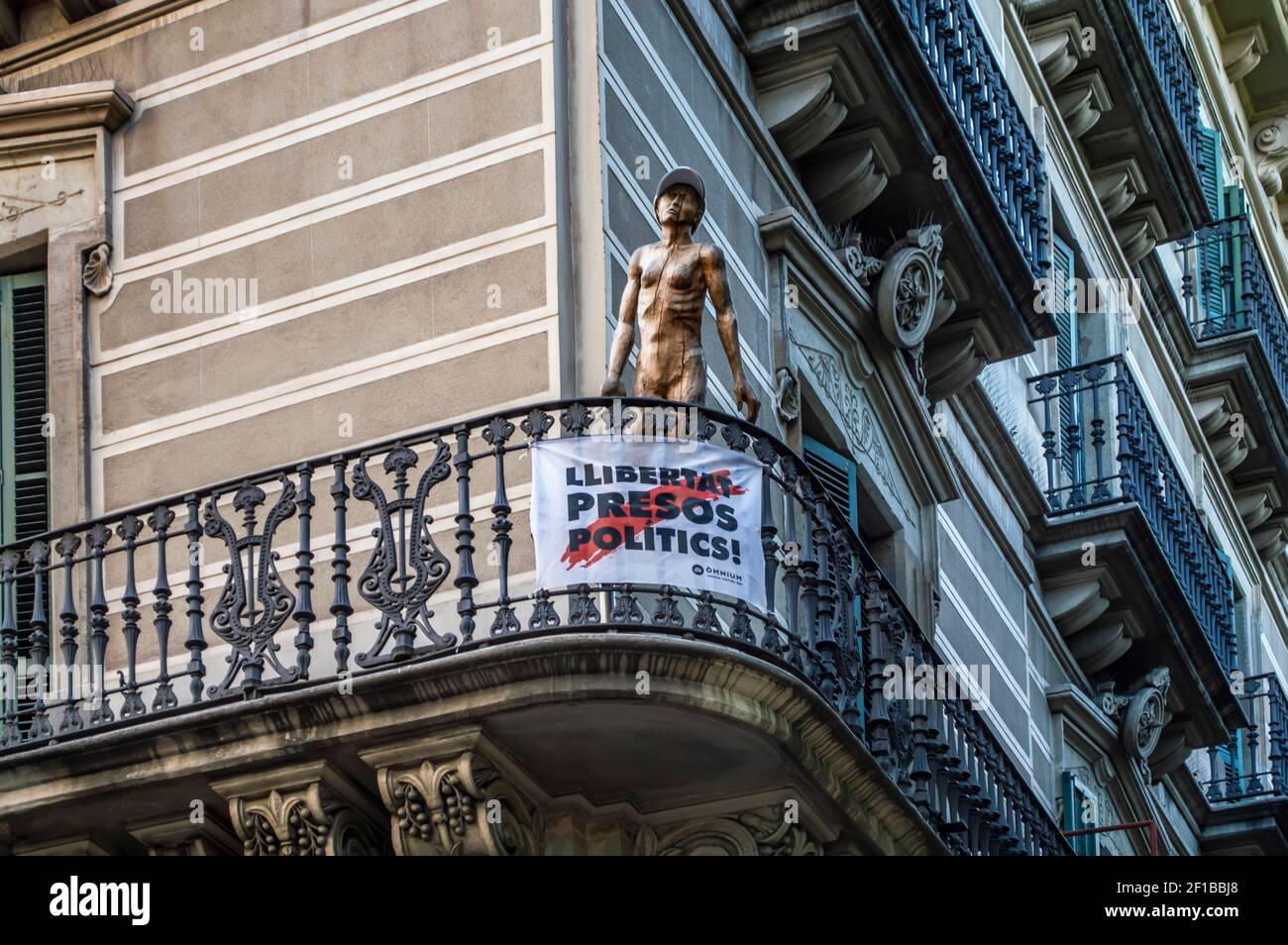 Ein katalanisches Protestbanner und eine Skulptur in Barcelona, Katalonien, Spanien. Der Text sagt "Freiheit für politische Gefangene". Stockfoto