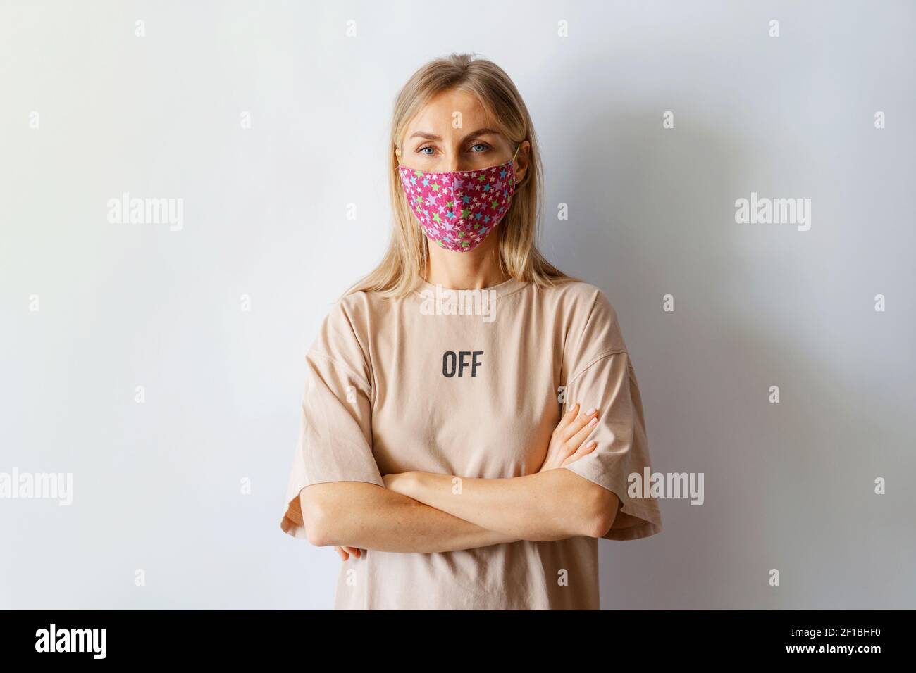 Nahaufnahme Porträt auf einem blassen Hintergrund einer kaukasischen Frau in einer schützenden medizinischen Textil handgemachte Maske. Neues normales Leben Stockfoto