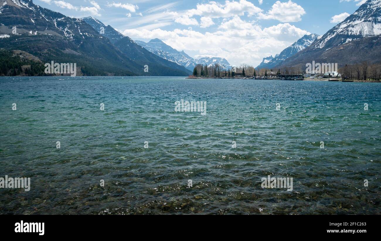 Kleine Stadt am Ufer des Sees, umgeben von Bergen, aufgenommen im Waterton National Park, Alberta Stockfoto