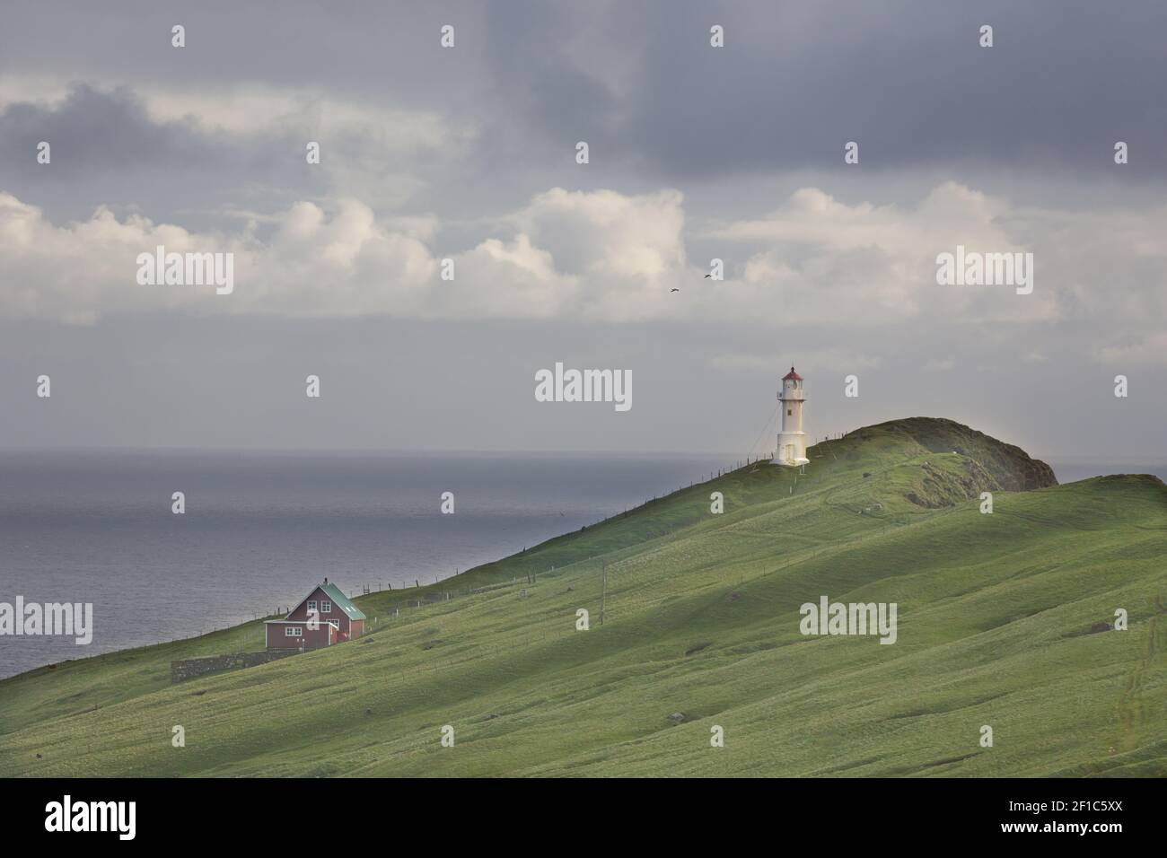 Schöne dramatische Landschaft auf den Färöern. wolkiger Himmel, Leuchtturm, Gras Stockfoto
