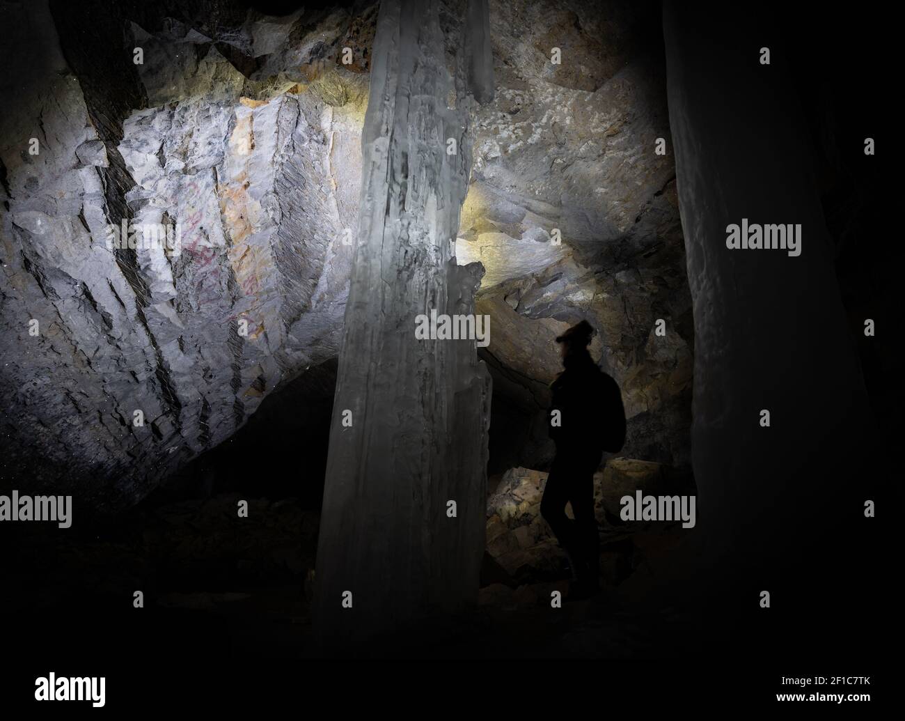 Wanderer erkunden dunkle Höhle Beleuchtung es nur mit Stirnlampe. Gedreht in den kanadischen Rockies auf dem Kananaskis Ice Cave Trail, Alberta, Kanada Stockfoto