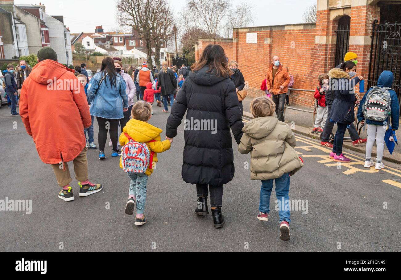 Brighton UK 8th March 2021 - Glückliche Kinder und Eltern kommen heute Morgen an der St. Luke's Primary School in Brighton an, da die Sperrbeschränkungen der Regierung in England allmählich gelockert werden. Schulen und Colleges werden für alle Schüler heute in ganz England wieder geöffnet : Credit Simon Dack / Alamy Live News Stockfoto