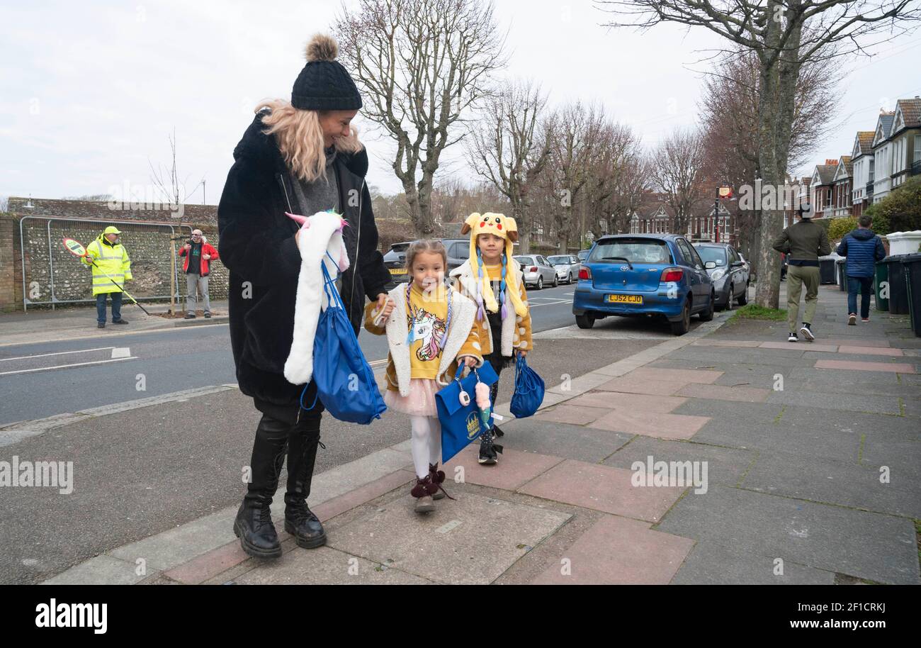 Brighton UK 8th March 2021 - Glückliche Kinder und Eltern kommen heute Morgen an der St. Luke's Primary School in Brighton an, da die Sperrbeschränkungen der Regierung in England allmählich gelockert werden. Schulen und Colleges werden für alle Schüler heute in ganz England wieder geöffnet : Credit Simon Dack / Alamy Live News Stockfoto