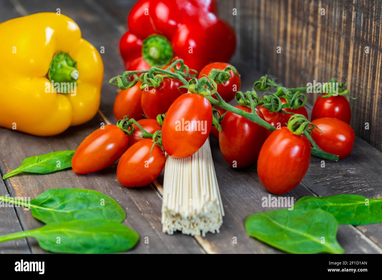 Nahaufnahme von rohen Pasta Spaghetti auf Holzhintergrund.frisches Bio-Gemüse mit ungekochter Pasta, gesundes Lebensmittelkonzept. Stockfoto