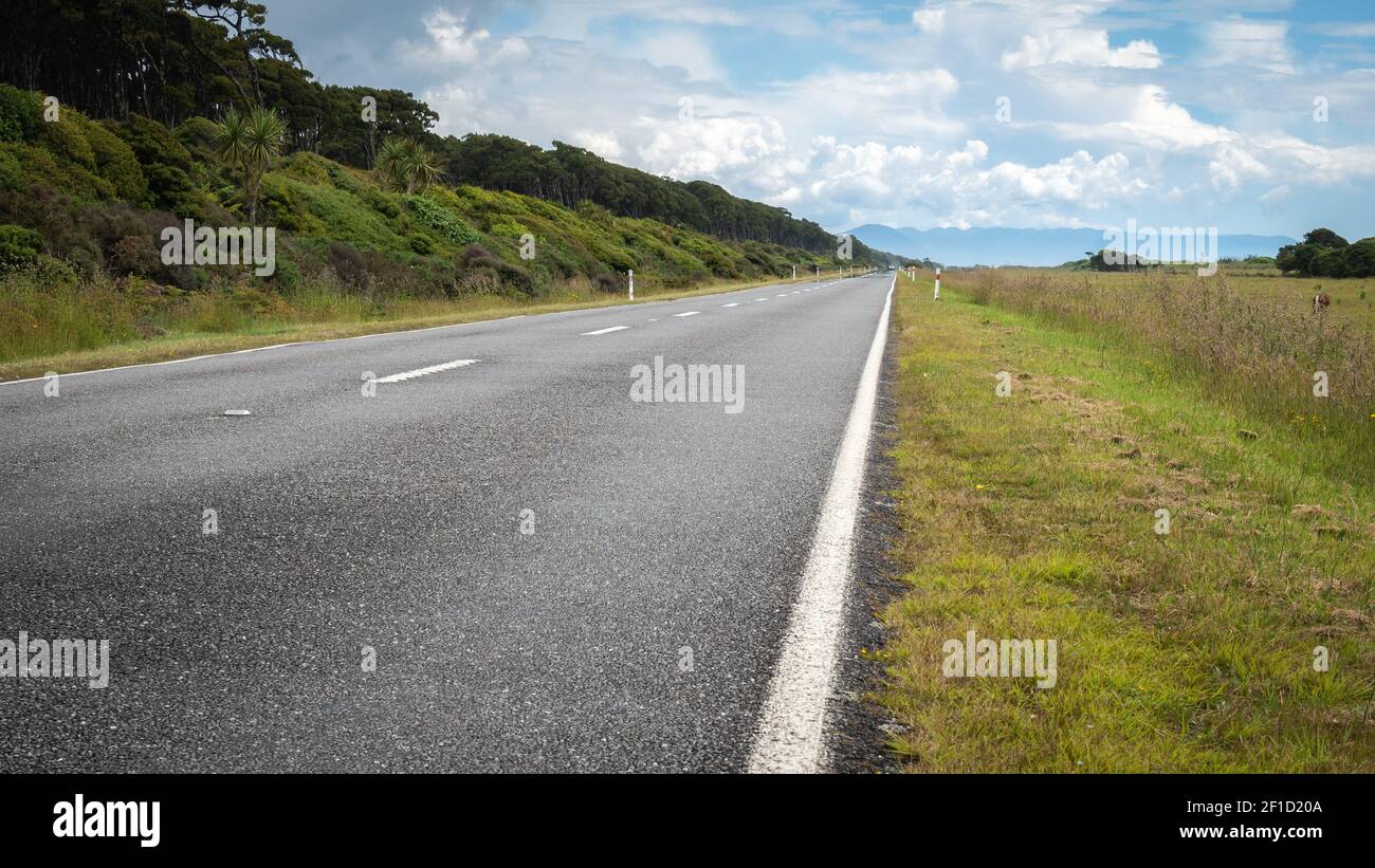 Straße, die in die Ferne führt (gerader Horizont). Aufgenommen an sonnigen Tagen an der Westküste Neuseelands Stockfoto