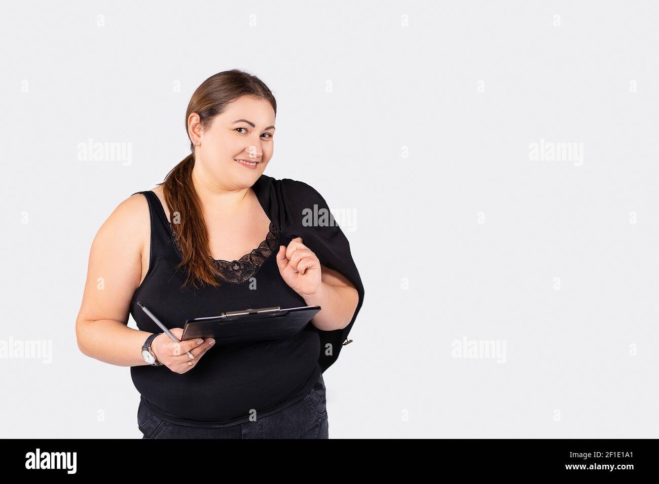 Porträt einer übergewichtigen Geschäftsfrau, mit Dokumenten in der Hand und einer Jacke auf der Schulter, schaut auf die Kamera. Isoliert auf weiß mit Seitenwerbung Stockfoto