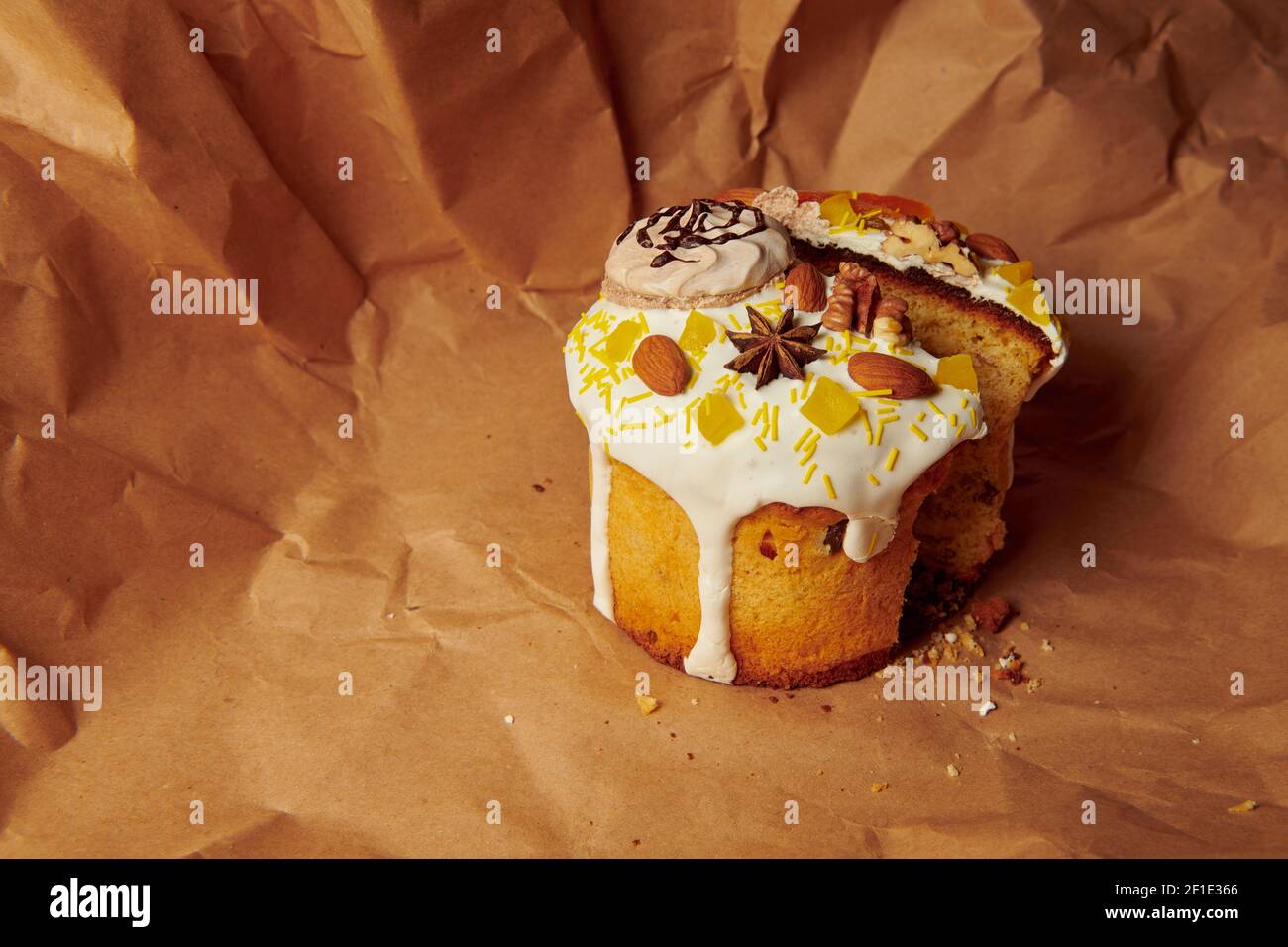 Geschnittener Osterkuchen auf braunem Papier. Handgemachte Panettone mit flüssigen Puderzucker Mandeln, Walnuss und Baiser verziert. Stockfoto