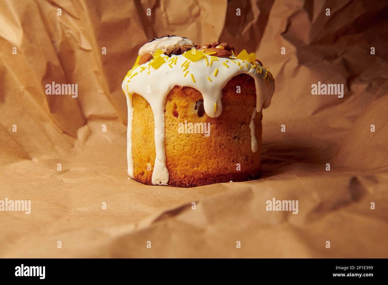 Osterkuchen auf braunem Papier. Handgemachte Panettone mit flüssigen Puderzucker Mandeln, Walnuss und Baiser verziert. Stockfoto