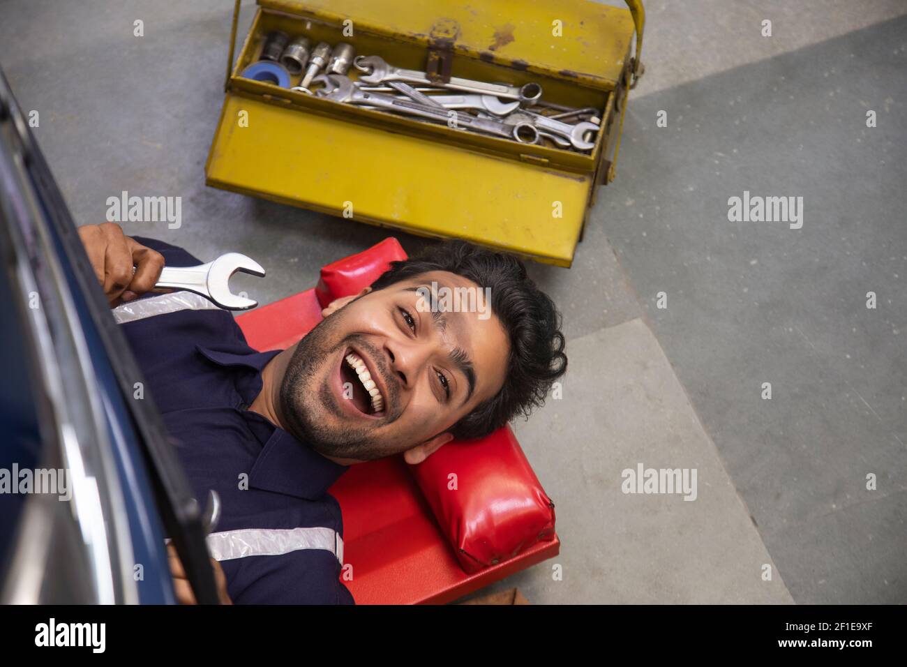 Draufsicht eines Mechanikers, der unter einem Fahrzeug arbeitet Stockfoto