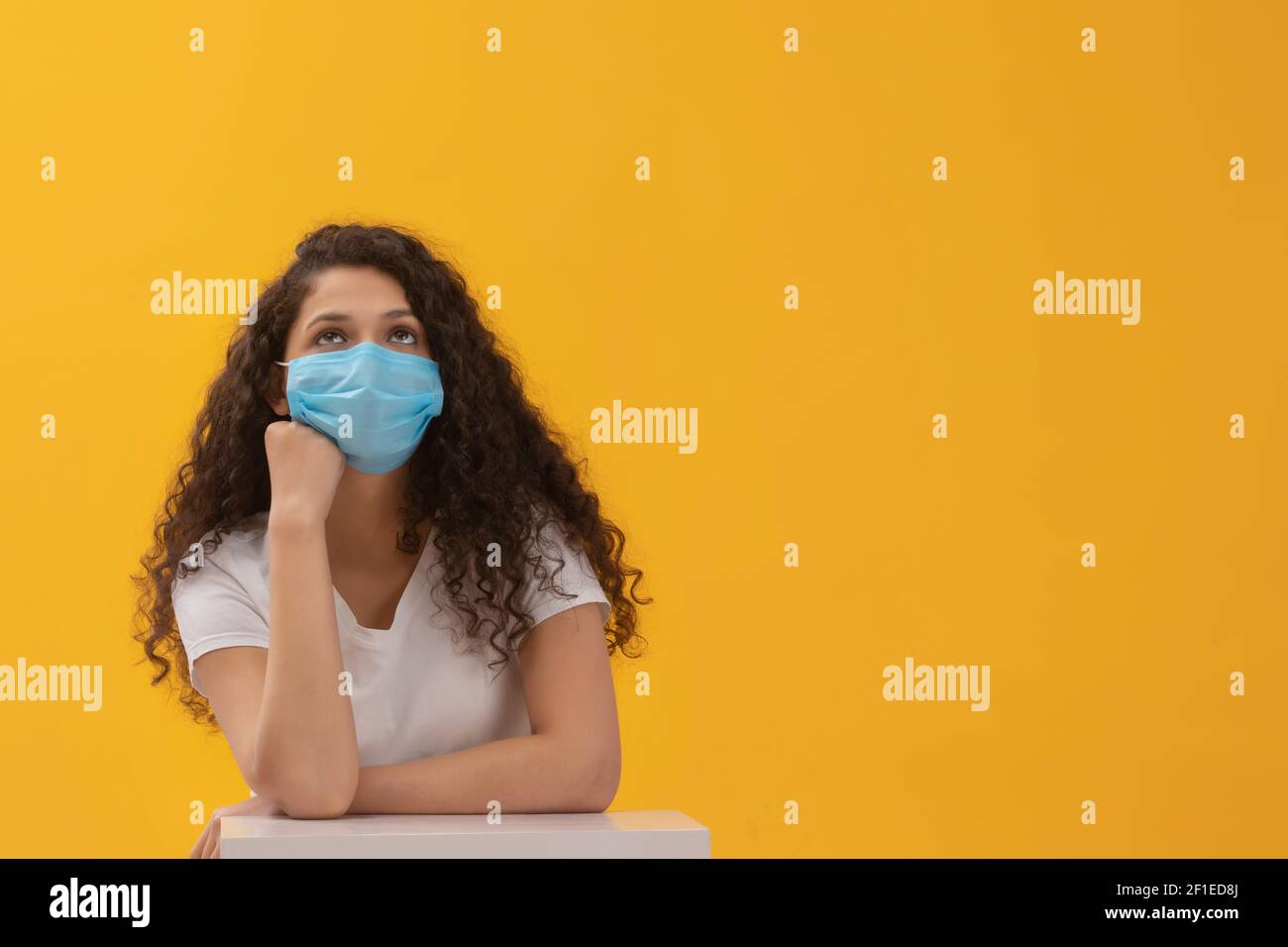 EIN TEENAGER TRÄGT GESICHTSMASKE SITZEND UND DENKEND Stockfoto