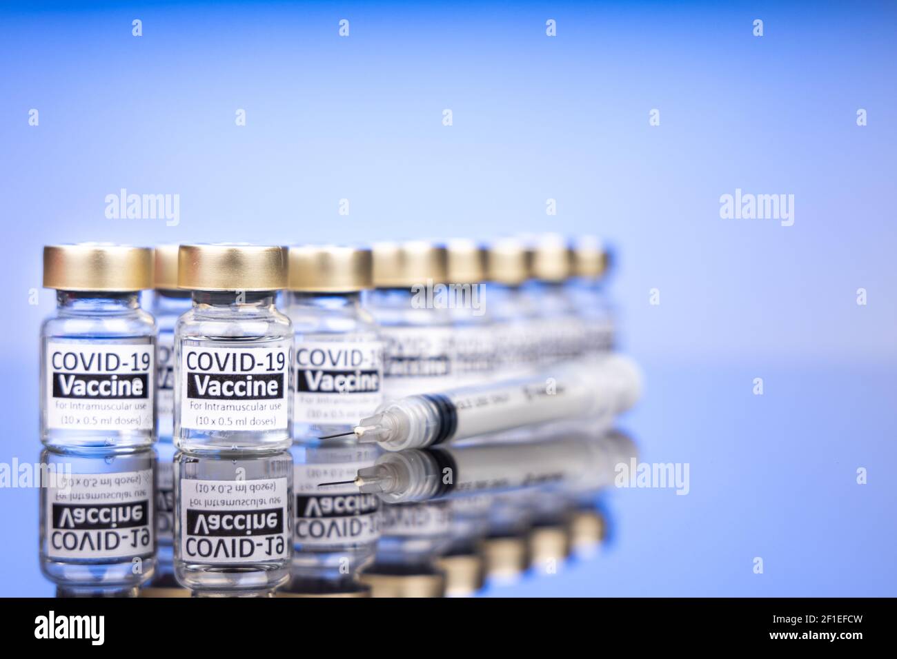 Multipe Covid-19 Impfstofffläschchen mit Spritzenkonzept auf reflektierender Oberfläche. Konzentrieren Sie sich auf die erste Reihe mit geringer Schärfentiefe Stockfoto