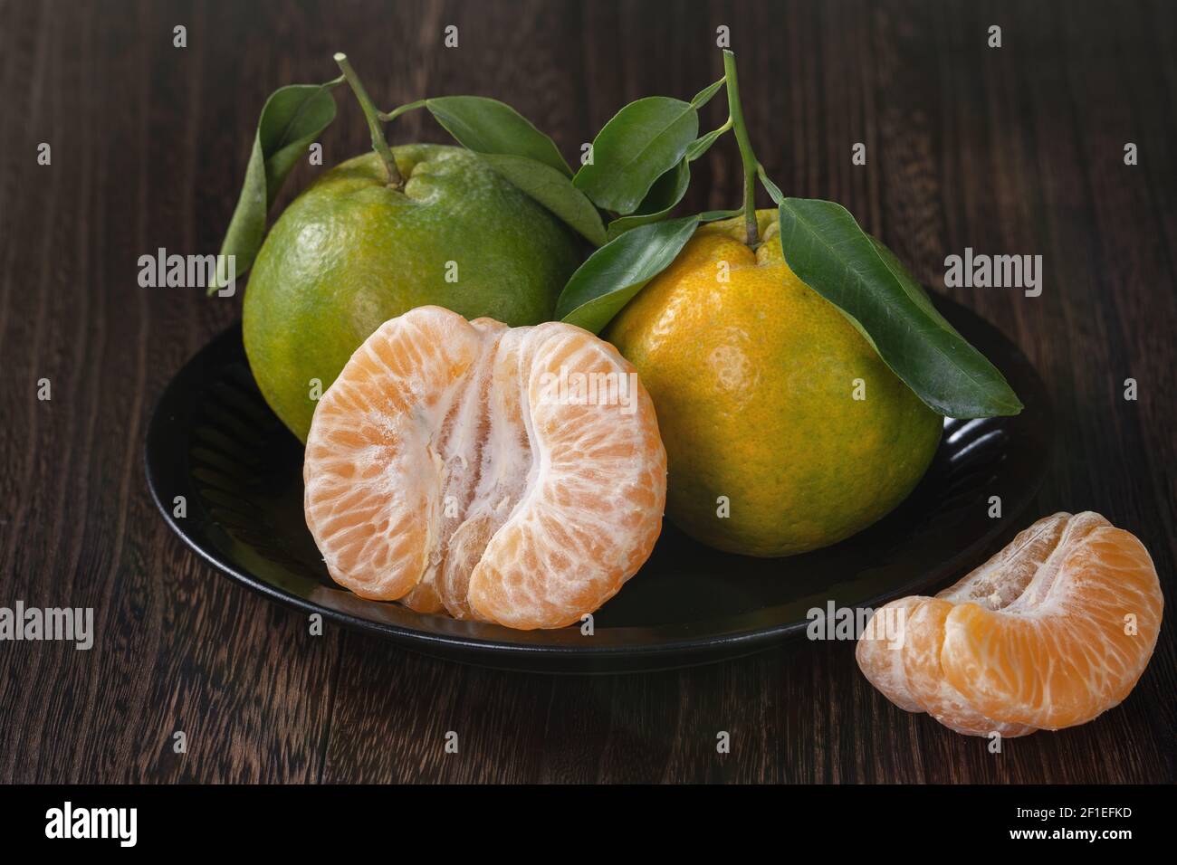 Frische grüne Mandarine Mandarine orange mit frischen Blättern auf dunklen Holztisch Hintergrund Ernte Konzept. Stockfoto