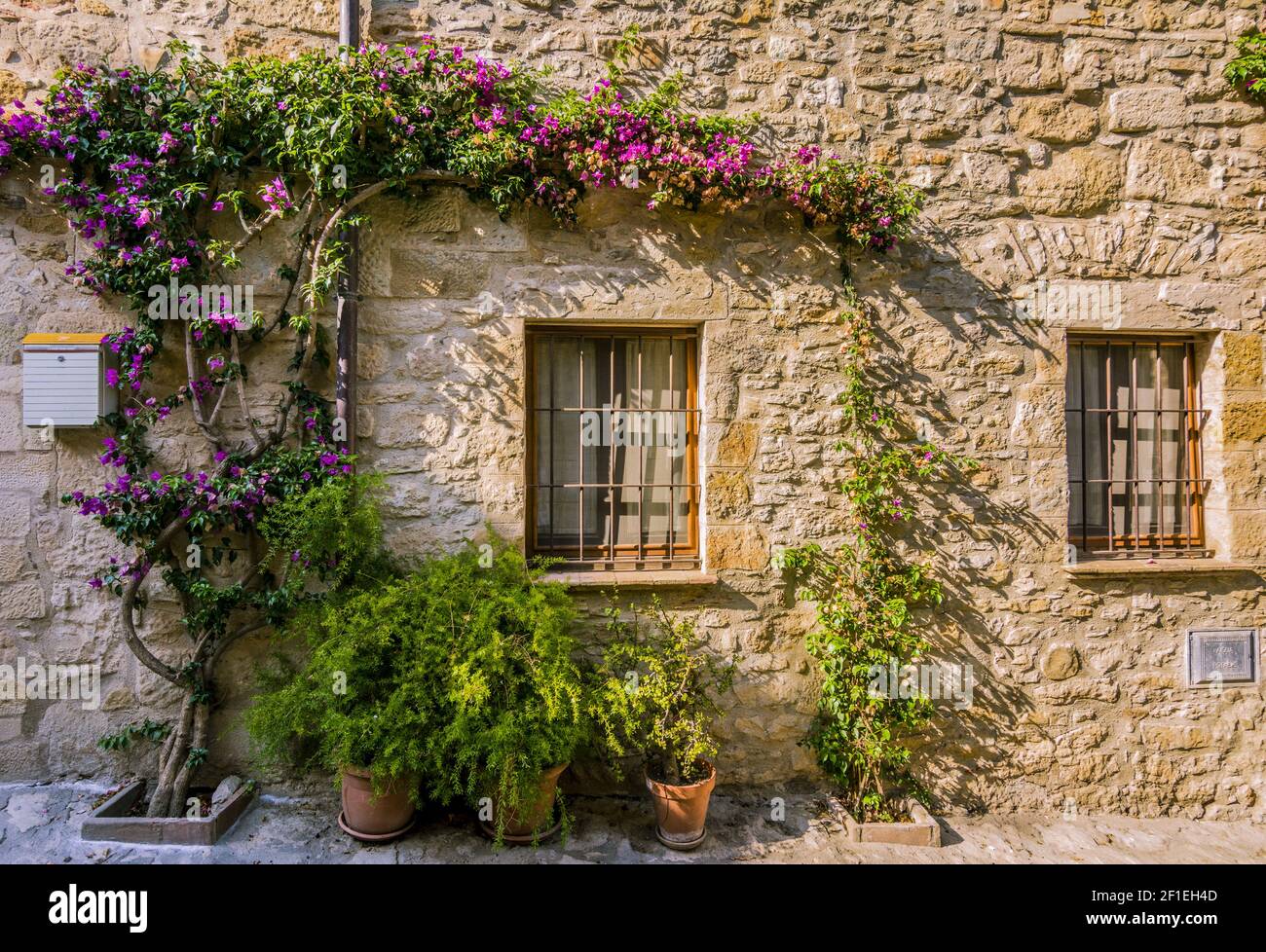 Fenster mit Bars an einer Steinfassade in der mittelalterlichen Stadt Peratallada, Spanien Stockfoto