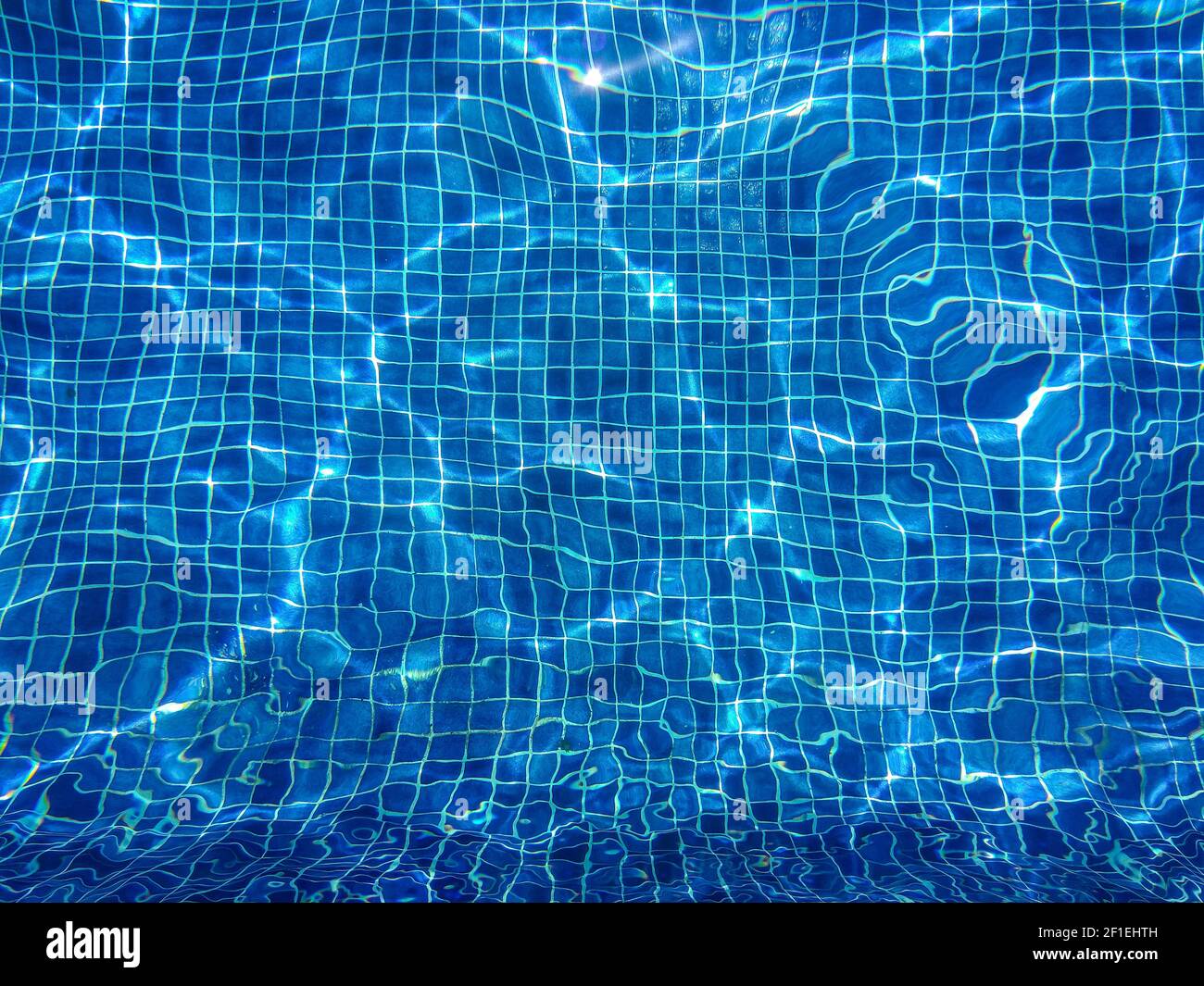 Zusammenfassung Hintergrund, Wasser Wellen und Linien des blauen Kacheln im Pool mit glänzenden Sonnenlicht Reflektion Stockfoto