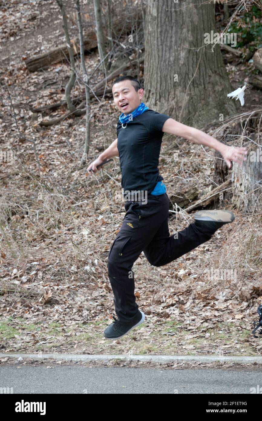 Ein sportlicher, flink junger chinesisch-amerikanischer Mann spielt Jianzi in einem Park in Queens, New York City. Stockfoto