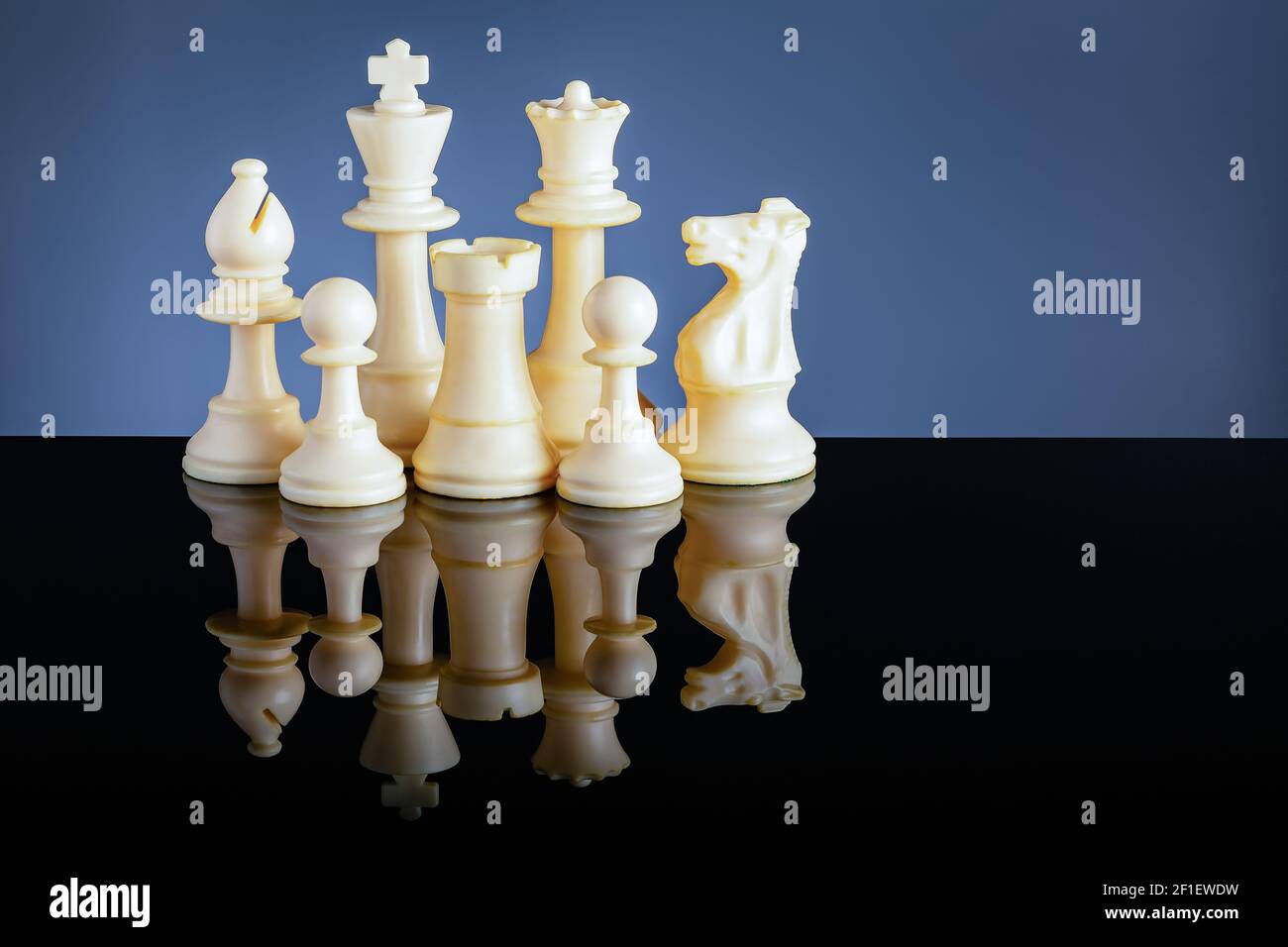 Weiße Schachfiguren auf schwarzem Acryl mit Reflektion und Blau Hintergrund Stockfoto