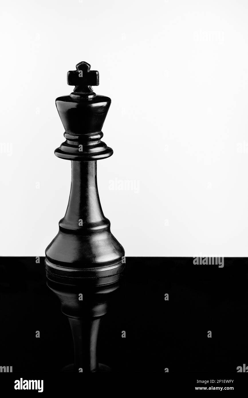 Black King auf schwarzem Acryl mit Reflektion und weißem Hintergrund Stockfoto
