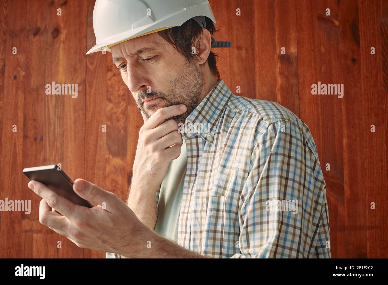 Porträt eines besorgten männlichen Arbeiters mit Handy, Lesen von Textnachrichten, selektiver Fokus Stockfoto