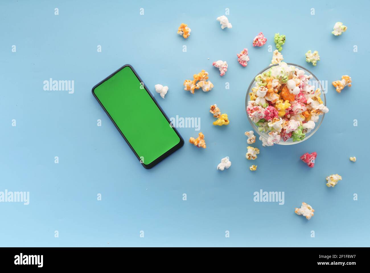 Draufsicht auf Smartphone und Popcorn auf blauem Hintergrund Stockfoto