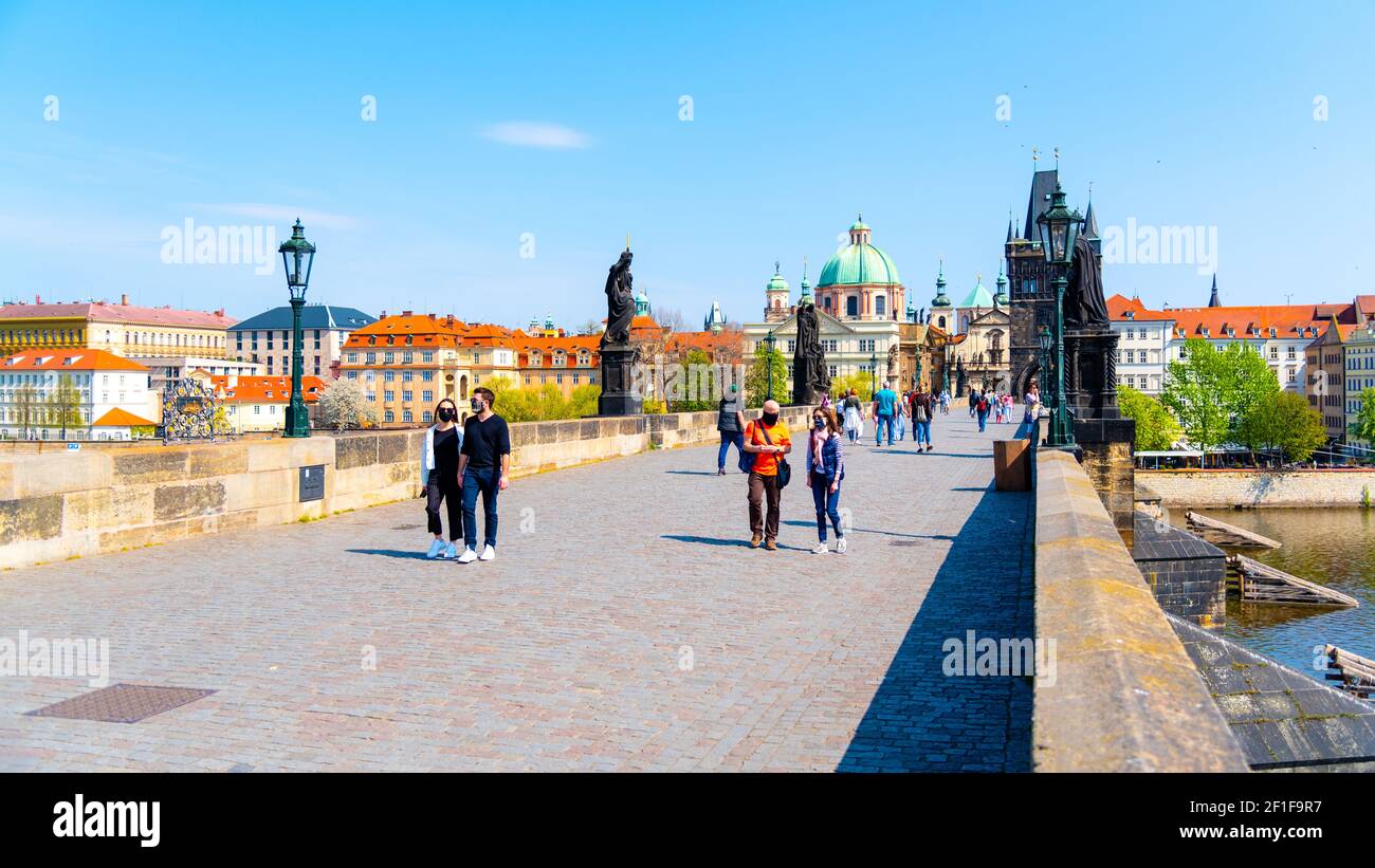 PRAG, TSCHECHISCHE REPUBLIK - 17. APRIL 2020: Menschen mit Gesichtsmasken auf der Karlsbrücke in Prag. Pandemie der Coronavirus-Krankheit 2019 - COVID-19 Stockfoto