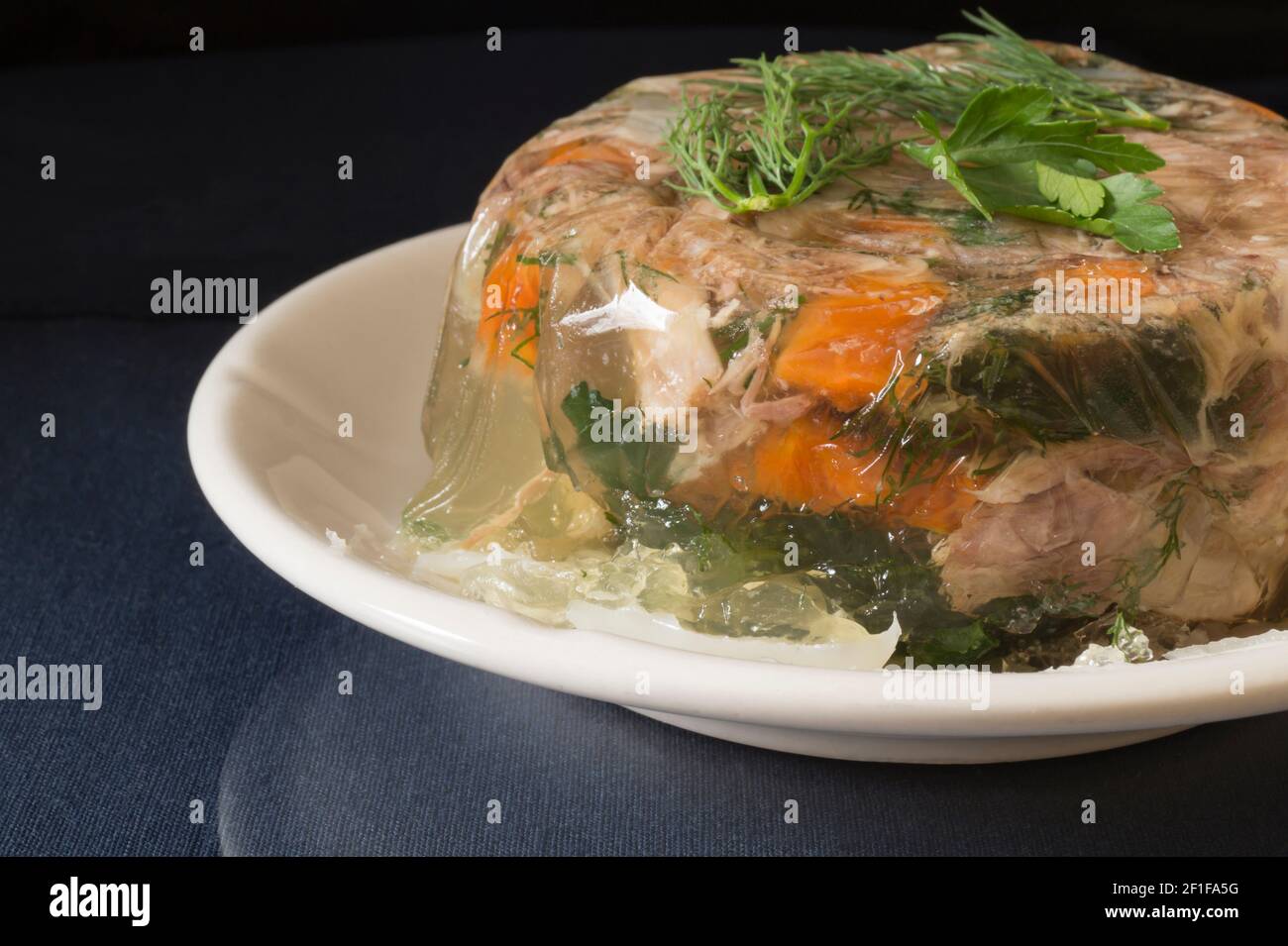 Aspic Fleisch in einem weißen Teller auf dem Tisch. Essen auf schwarzem Hintergrund Stockfoto