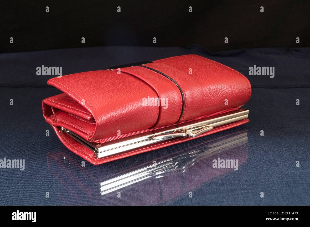 Die rote Brieftasche liegt mit der Reflexion auf dem Tisch. Objekte auf schwarzem Hintergrund Stockfoto