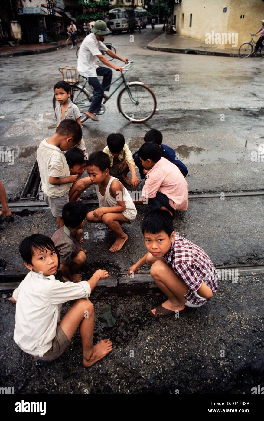 Kinder, die versuchen, einen Funken aus Straßenbahnschienen zu erzeugen, Hanoi, Nordvietnam, Juni 1980 Stockfoto