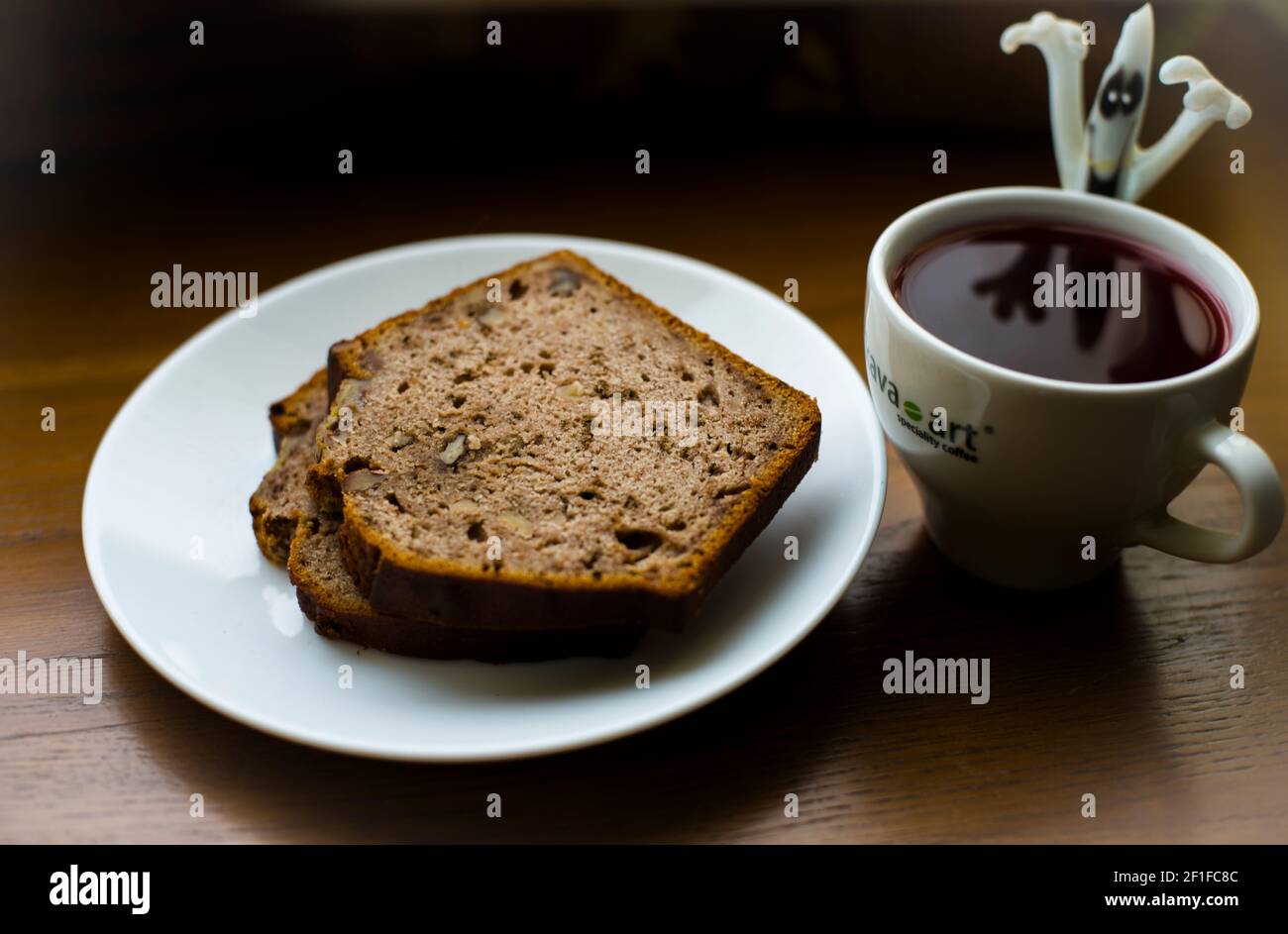 Ein Spielzeug Geist, reflektiert in der Tasse Kaffee, und ein Stück Kuchen Stockfoto