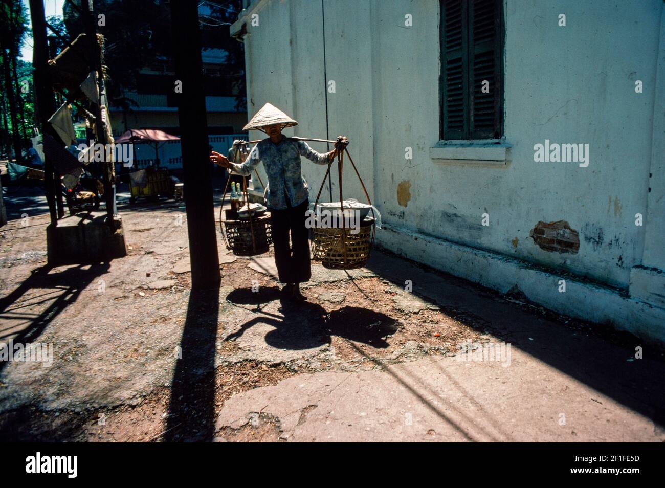 Eine Frau, die Straßenessen trägt, um ihren Stand zu errichten, Ho Chi Minh City, Vietnam, Juni 1980 Stockfoto