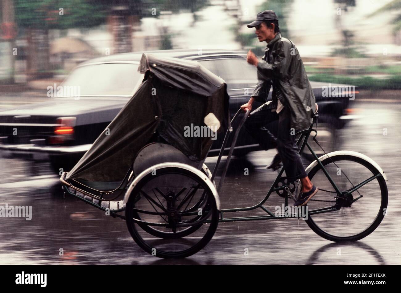 Ein Pedal-Cyclo-Fahrer während eines Monsunregens, Ho Chi Minh City, Vietnam, Juni 1980 Stockfoto