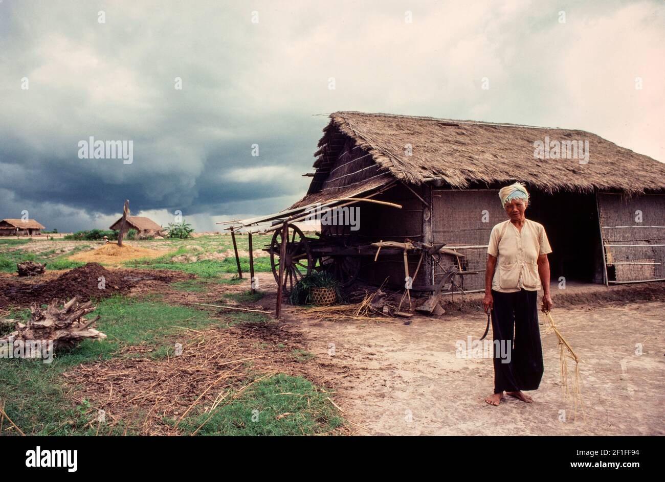 Eine Frau steht vor ihrem Haus, als sich eine Monsunwolke nähert, ländliches Südvietnam, Juni 1980 Stockfoto