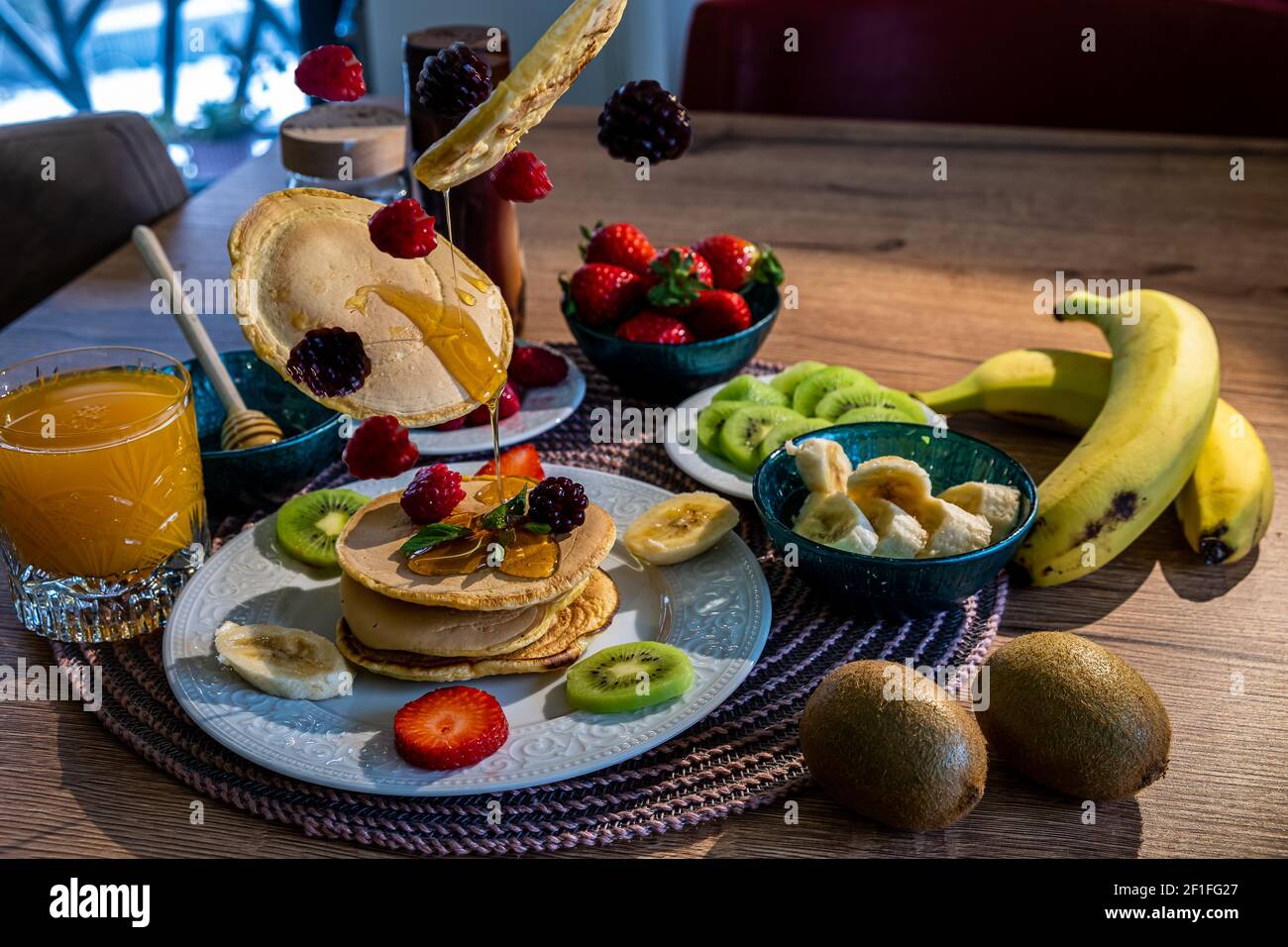 Fliegende Pfannkuchen mit Brombeere, Himbeere, Erdbeere, Minze und Honig Stockfoto