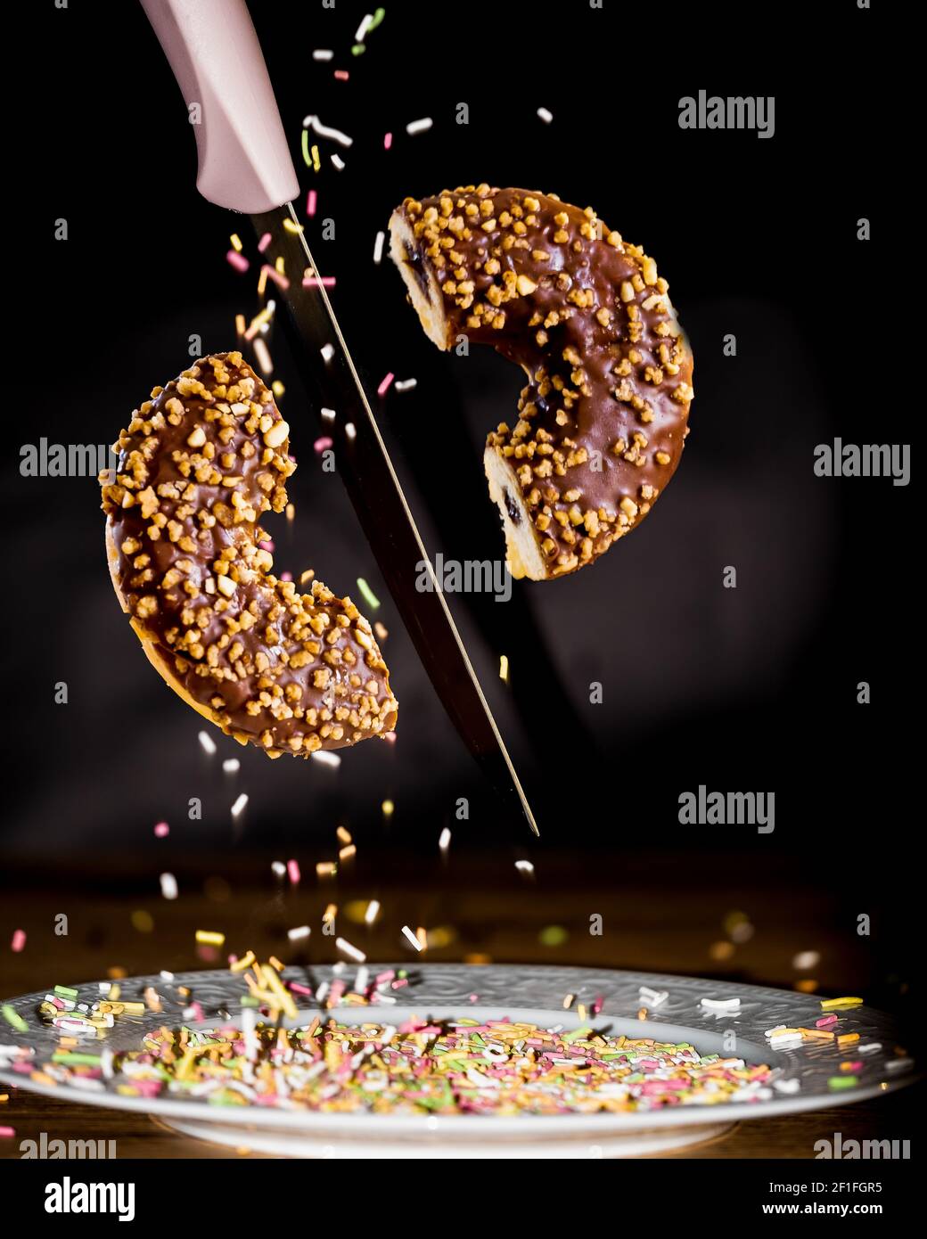 Halb geschnittener Donut mit Messer in der Luft Stockfoto